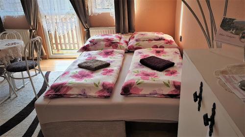 a room with two beds with pink flowers at Bihari Vendégház in Felsőtárkány