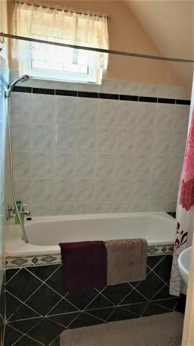 a bathroom with a bath tub and a window at Bihari Vendégház in Felsőtárkány