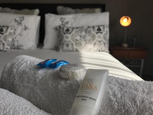 a white bed with a bottle of lasana products on it at Waterfall Bed & Breakfast in Midrand