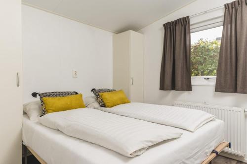 2 bedden in een witte kamer met gele kussens bij Valk 4 persons in Rijssen