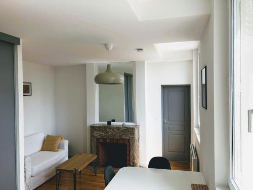 sala de estar con chimenea y sofá blanco en Le seize, en Châlons-en-Champagne