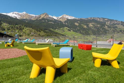 a group of chairs sitting in the grass with mountains at Hotel Blü Gastein in Bad Hofgastein
