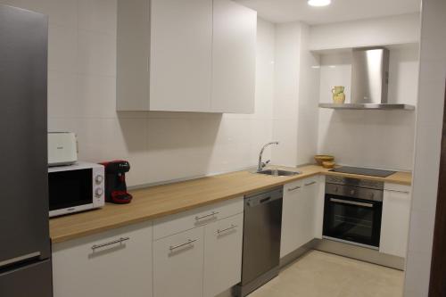 a kitchen with white cabinets and a sink and a microwave at Apartamentos rurales 'Los Soportales' in Tendilla