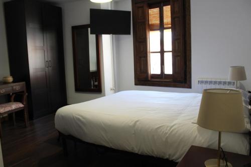 a bedroom with a white bed and a window at Apartamentos rurales 'Los Soportales' in Tendilla