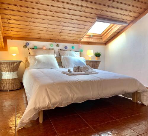 a bedroom with a large white bed with a wooden ceiling at Apartment Praia Arrifana with BALCONY and SEA VIEW in Aljezur