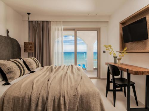 Schlafzimmer mit einem Bett, einem Schreibtisch und einem Fenster in der Unterkunft Boletsos Beach in Argassi