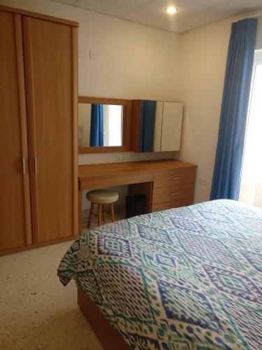 a bedroom with a bed and a desk and a mirror at BEACHFRONT with Seaviews Apartment No56 Award Winner Unbeatable Location for Closeness to the Sea Ideal for Guests looking for Winter Spring and Autumn Breaks in Sunny Malta Also Ideal for Coastal Hikers in Mellieħa