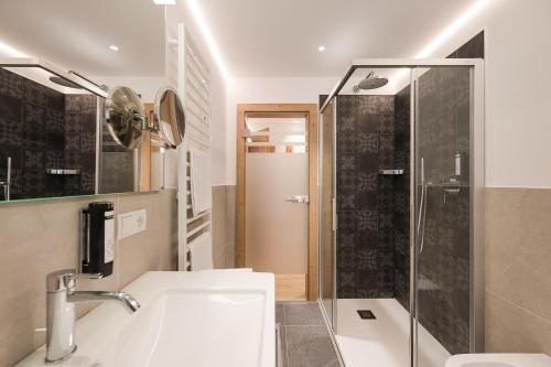 a bathroom with a sink and a glass shower at Hotel Alpenhof in Tirolo