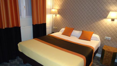 a bedroom with a bed with two orange pillows at Hotel d'Amiens in Paris