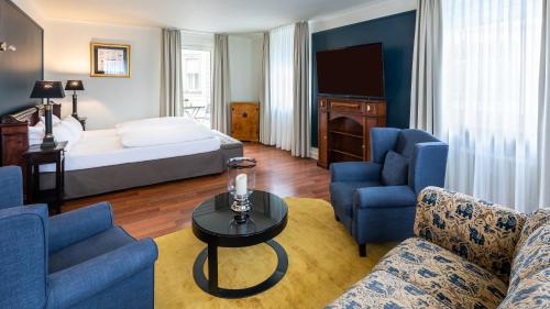 a hotel room with a bed and blue chairs at Hotel Würzburger Hof **** in Würzburg