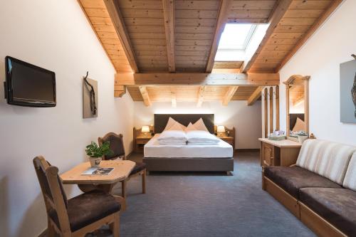 a bedroom with a bed and a couch and a table at Hotel Alpenhof in Tirolo
