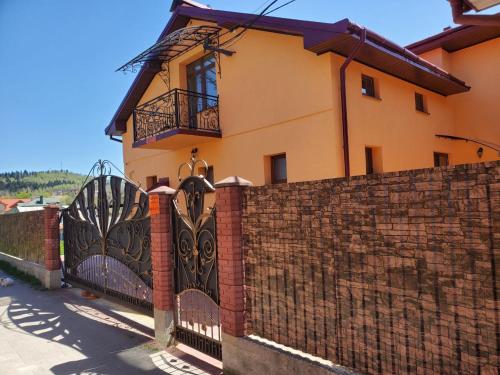 a brick fence with a gate in front of a house at Апартаменти "Ілона" в центрі Східниці in Skhidnitsa