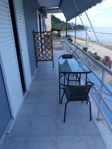 a balcony with a table and chairs and the beach at AGATHA appartments PALIOURIA in Kókkinon Nerón
