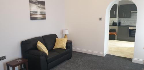 a living room with a black couch and a kitchen at Glentworth Holiday Apartments in Tenby