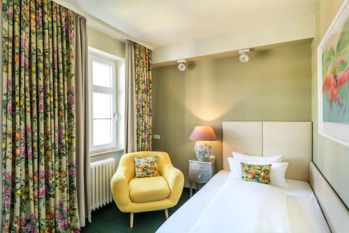 a bedroom with a bed and a chair and a window at Hotel Würzburger Hof **** in Würzburg