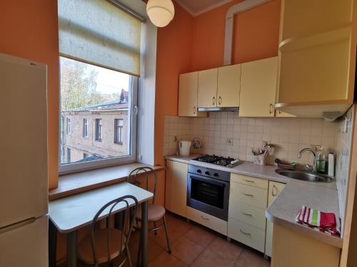 cocina con paredes de color naranja, lavabo y ventana en Cietokšņa 34 en Daugavpils