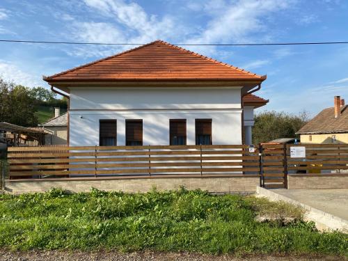 a white house with a wooden fence in front of it at Lukács Vendégház in Erdőhorváti