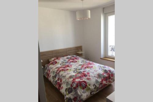 1 dormitorio con 1 cama con manta de flores en Meublé T2 Moderne en Hyper centre en Vittel