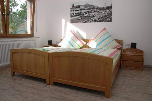 ein Holzbett mit Kissen darauf in einem Zimmer in der Unterkunft Ferienwohnung-Bine am Nürburgring in der Eifel in Quiddelbach