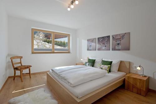 biała sypialnia z łóżkiem i krzesłem w obiekcie Appartement Rehkitz w mieście Ellmau