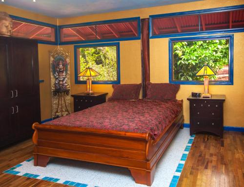 Pahoa的住宿－Hawaiian Balinese Temple House，一间卧室配有一张床、两盏灯和两扇窗户。