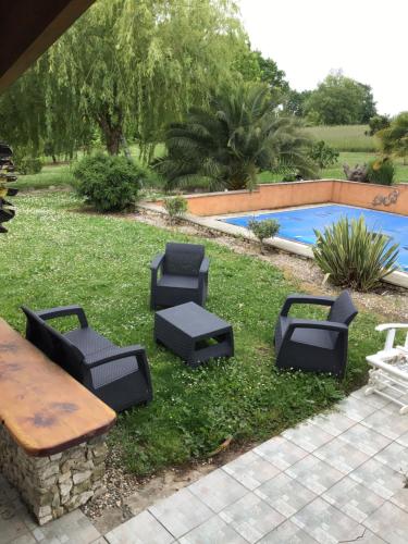 un patio trasero con mesa de picnic y sillas junto a una piscina en Chambre leo, en Xaintrailles