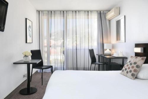 a hotel room with a bed and two tables and chairs at Best Western Hotel Mediterranee Menton in Menton