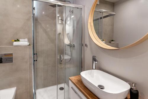 a bathroom with a shower and a sink and a mirror at Apartament Belona Gąski - 365PAM in Gąski