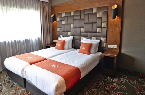um quarto de hotel com duas camas com almofadas laranja em XO Hotels Park West em Amesterdão