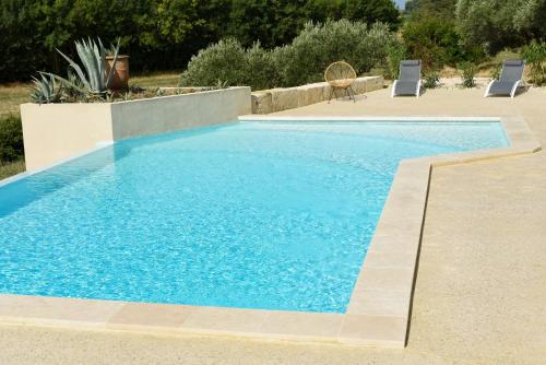 a swimming pool with blue water in a yard at La Bergerie de l'etang in Montels