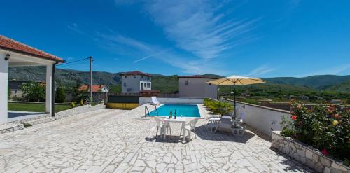 une terrasse avec une table, un parasol et une piscine dans l'établissement Villa Buna Breeze, à Blagaj