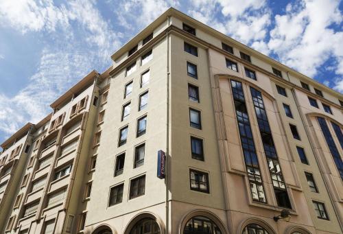 Un edificio alto con un reloj a un lado. en Citadines Presqu'île Lyon, en Lyon