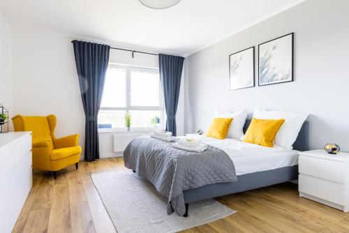 a bedroom with a bed and a yellow chair at Symphony Baltica Towers Apartamenty in Gdańsk