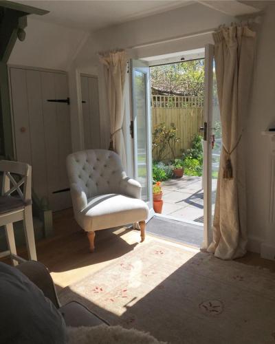 a living room with a white chair and a sliding glass door at Wrenscott in Chagford