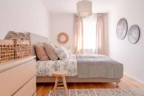 a white bedroom with a bed and a wooden stool at Dach.Loft Spitz in der Wachau in Spitz