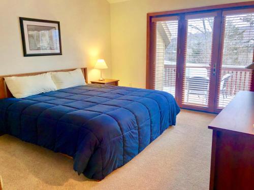 a bedroom with a blue bed and a large window at C6 Beautiful views from this Crawford Ridge Townhome a short walk from the slopes in Carroll