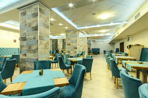 a restaurant with wooden tables and blue chairs at Villa Dea & Villa Ina - Villas & SPA Park in Velingrad in Velingrad