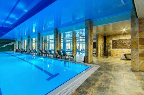 a large swimming pool in a building with chairs at Villa Dea & Villa Ina - Villas & SPA Park in Velingrad in Velingrad