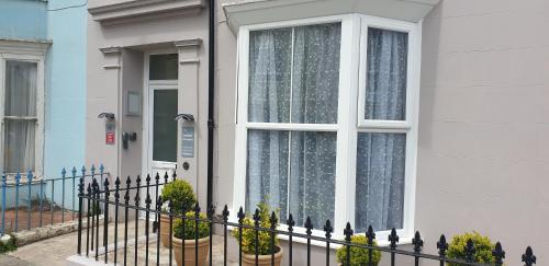 a white house with a window and a fence at Glentworth Holiday Apartments in Tenby