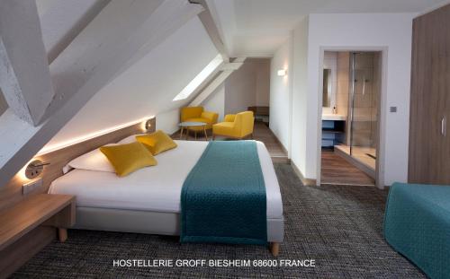 ein Hotelzimmer mit einem Bett und gelben Stühlen in der Unterkunft Aux Deux Clefs Hostellerie Groff in Biesheim