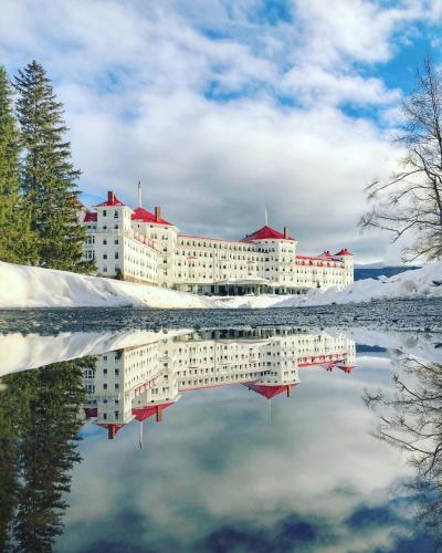 a reflection of a building in a body of water at F3 Fairway Village Condo with great mountain views, 8 minute walk from Omni Mount Washington Hotel! in Carroll