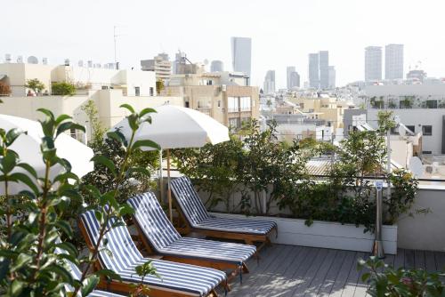 a row of chairs and an umbrella on a balcony at The Saul in Tel Aviv