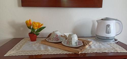 a coffee maker and two cups and a vase of flowers at Agriturismo Le Chicche di Mafalda in Montemerano