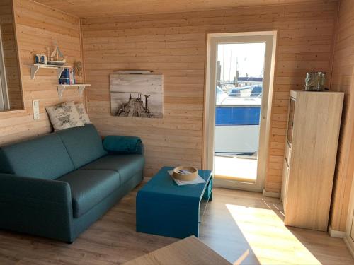 a living room with a blue couch and a window at Hausboot Bosse in Burgstaaken