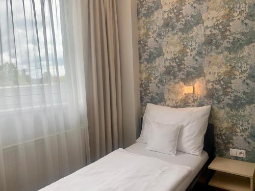 a bed in a room with a window and a pillow at Hotel Abácie & Wellness in Valašské Meziříčí
