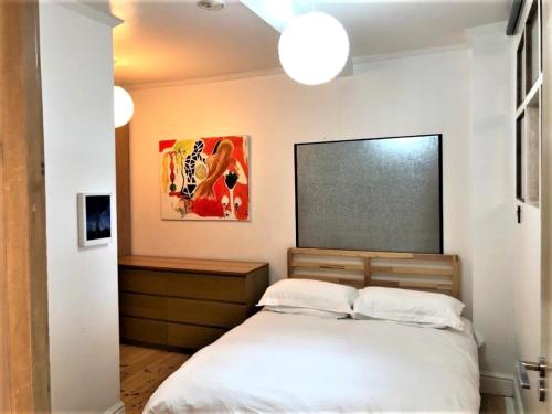 Schlafzimmer mit einem Bett und einer Tafel an der Wand in der Unterkunft Splendid 1 Bedroom Flat + Terrace (Kentish Town) in London
