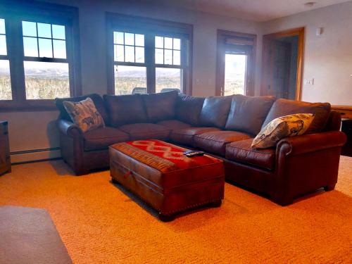 a living room with a leather couch and an ottoman at M1 Luxury home a short walk from the Mount Washington Hotel AC heated floor stunning views in Carroll