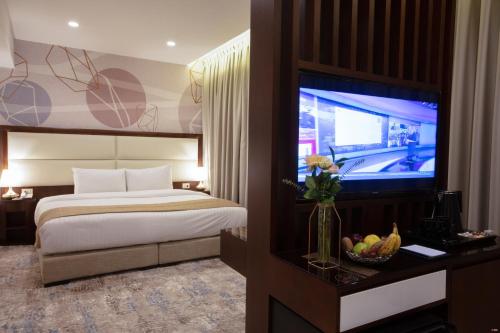 a hotel room with a bed and a flat screen tv at Seas Hotel Amman in Amman