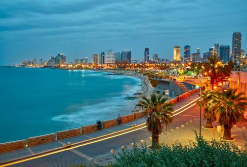 a view of the ocean and a city at night at The Saul in Tel Aviv
