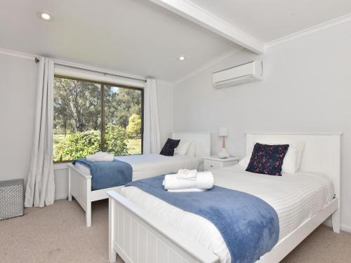 two beds in a white room with a window at Blaxlands Homestead - Nothing is closer opposite Hope Estate with Wifi and Pool plus Fireplace in Pokolbin